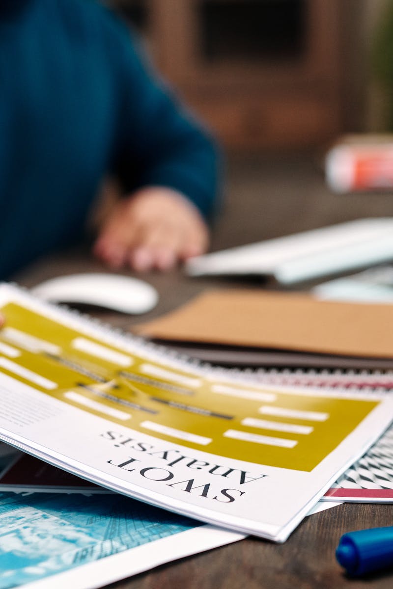 A person examines a SWOT analysis paper on a desk, focused on business strategy and planning.